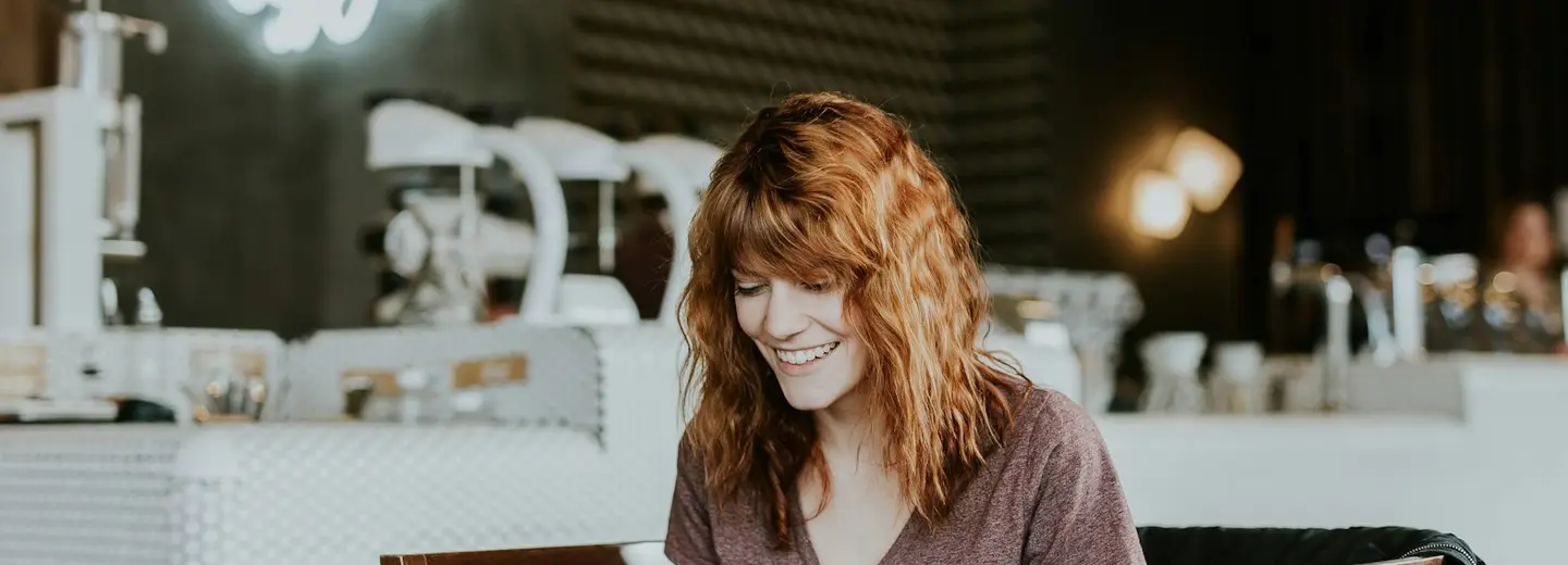 Freelancer smiling while working on a laptop in a café