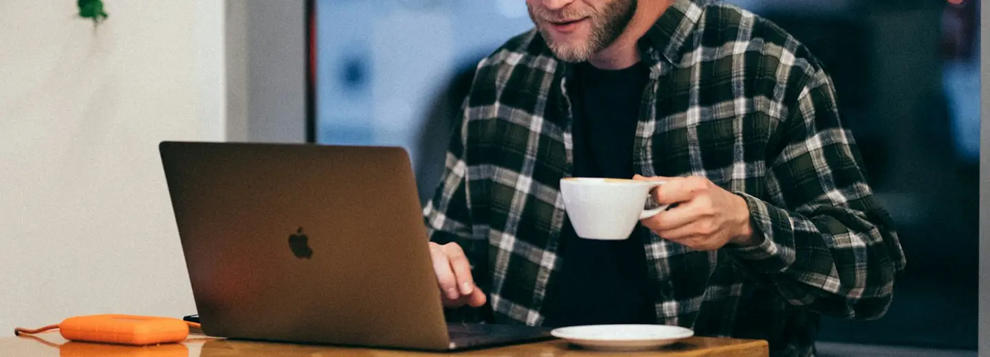 Freelancer having coffee while working on a laptop