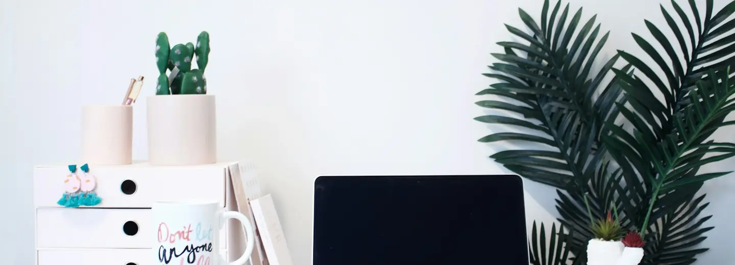 Bright desk with a laptop, mug and stacked notebooks