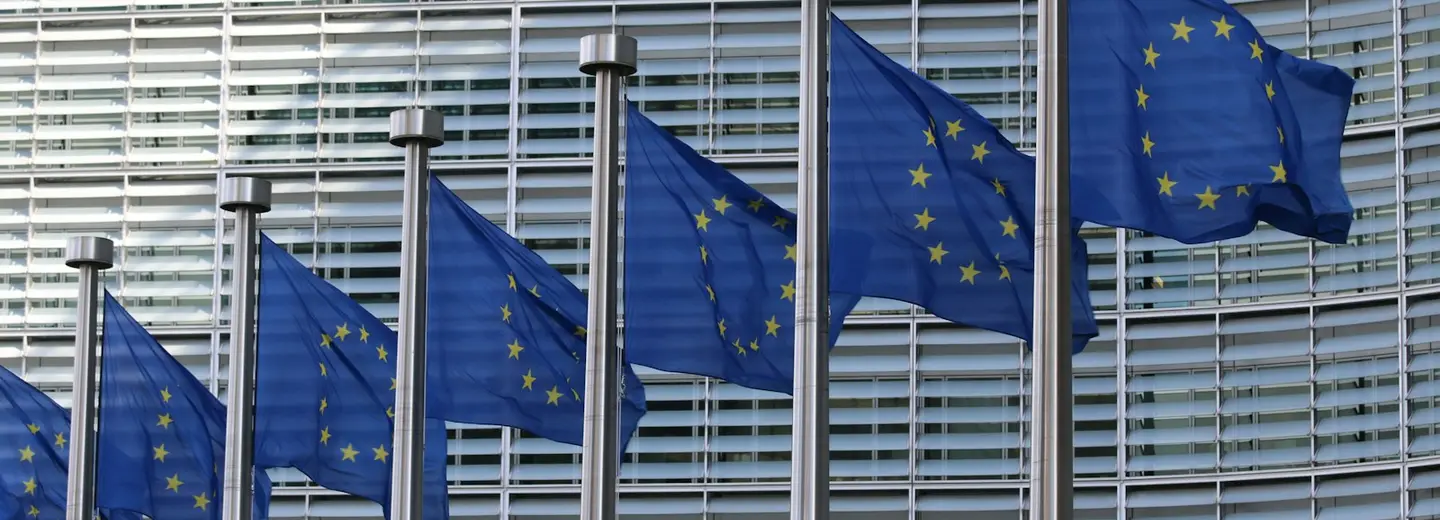 A row of EU flags flying outside the European Commission's glass headquarters in Brussels
