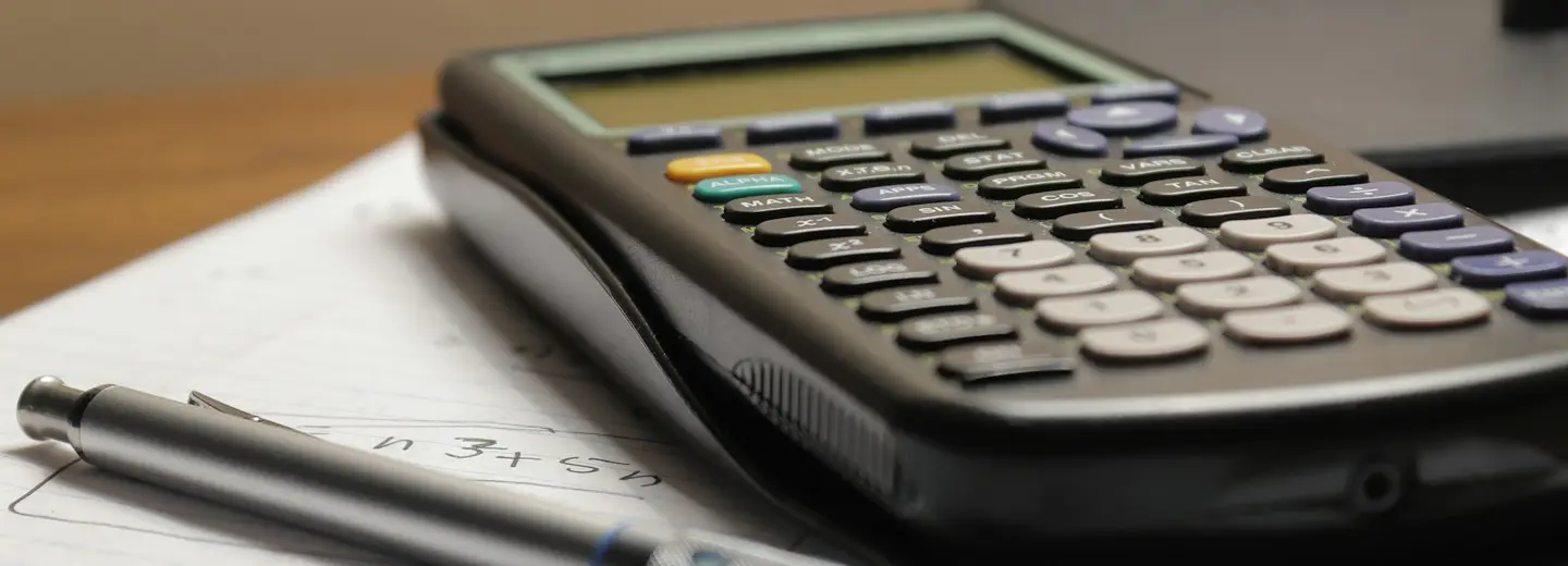 Calculator and pen resting on worksheets