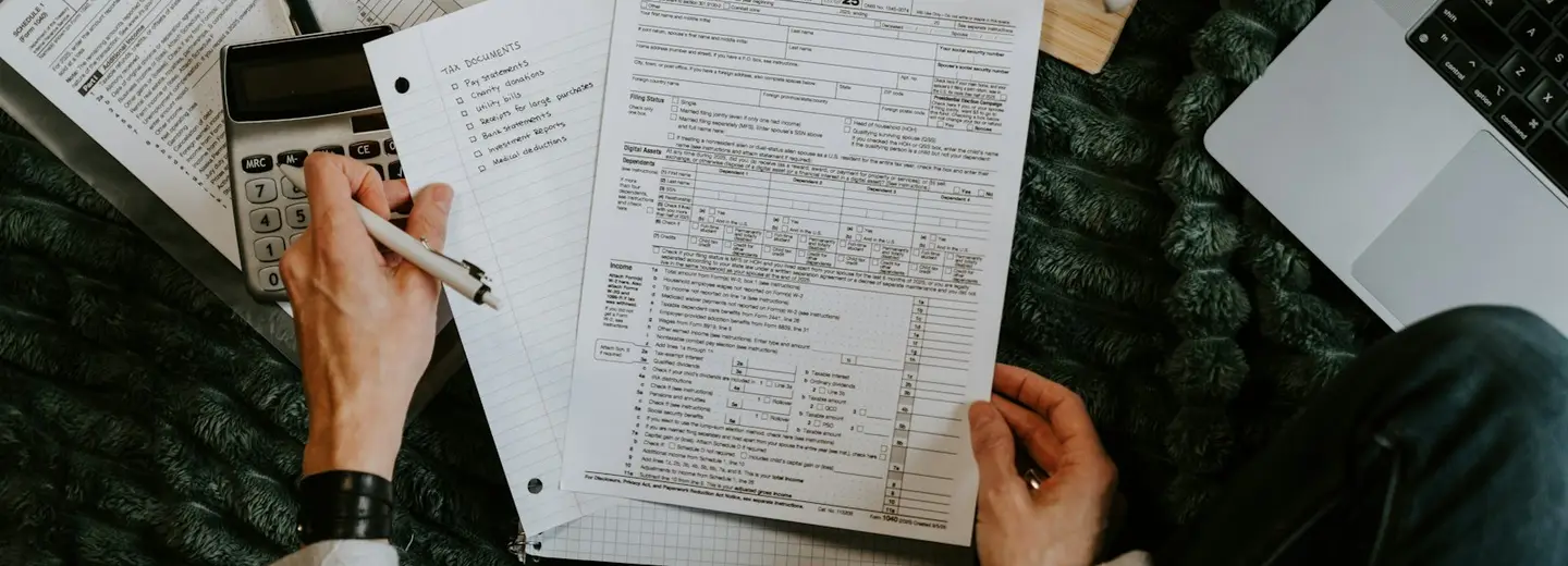 Hands reviewing financial documents with a calculator and coffee