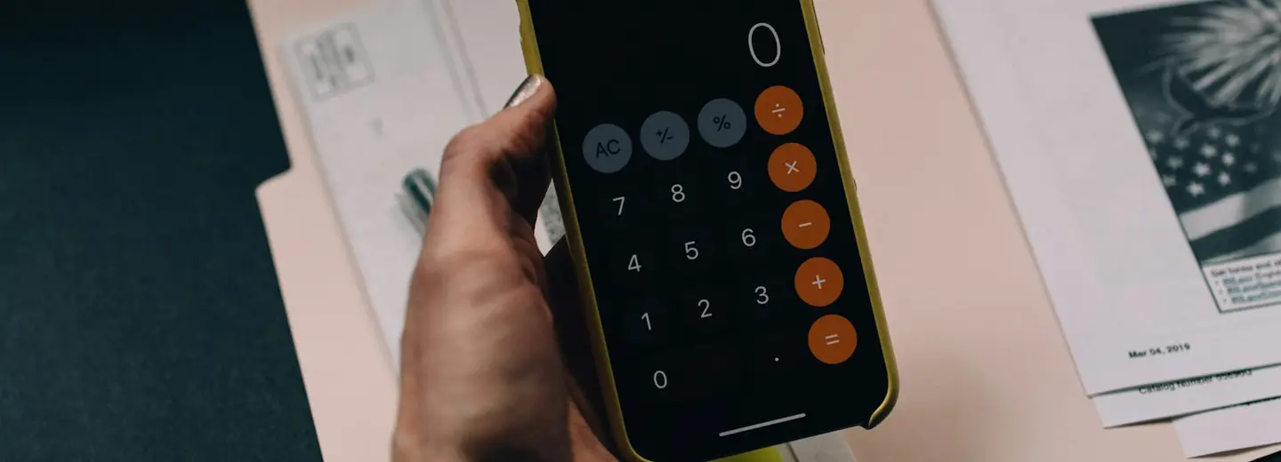 Hand using a phone calculator over a folder of documents