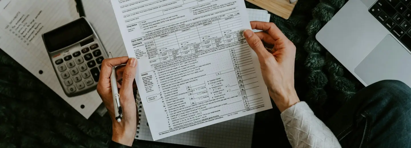 Hands checking a tax form with a calculator at hand