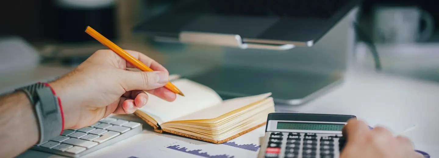 Hands working through numbers with a calculator and notebook