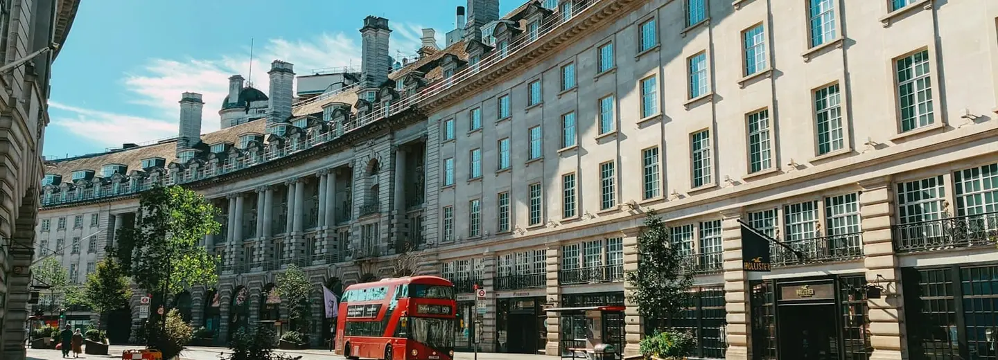 An empty curve of Regent Street in London with a red double-decker bus pulled in at the kerb